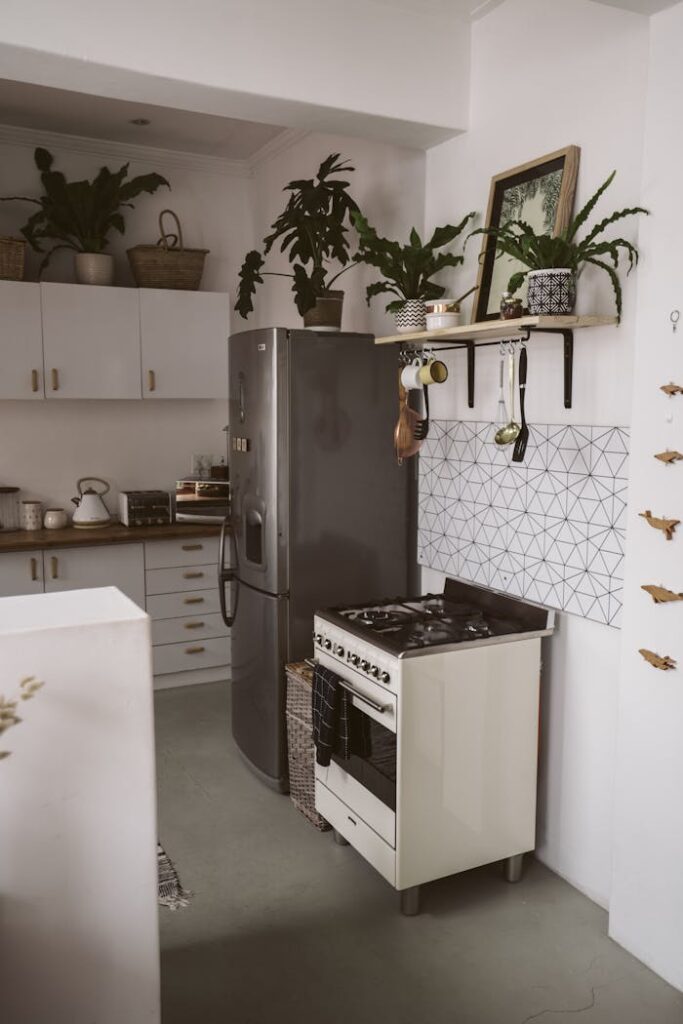 pexels-photo-4112602 A stylish kitchen featuring a sleek refrigerator, stove, and greenery for a modern touch.